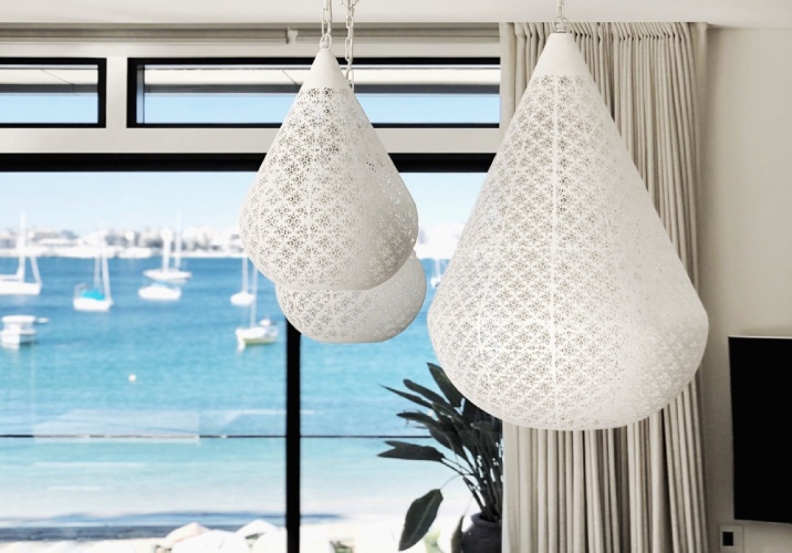 3 hanging white pendant lights in a room with windows leading to a beach.