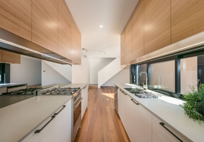 Large kitchen with timber floors, timber cabinetry, and white benchtops.