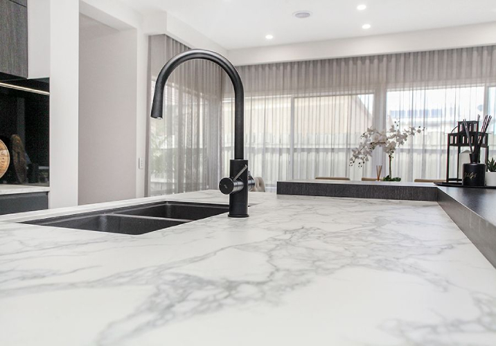 Marble kitchen benchtop with dark grey sink and tap.