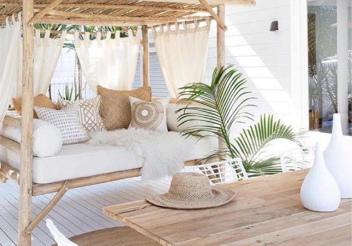 Daybed and wooden table on a white patio 