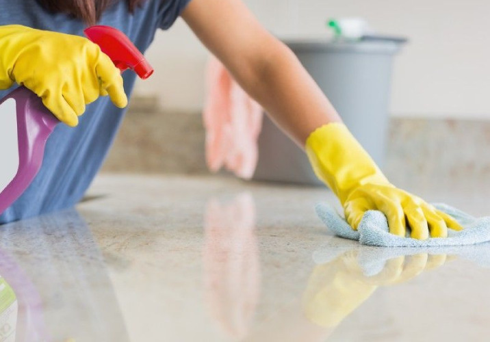 Women with yellow rubber gloves cleaning a surface