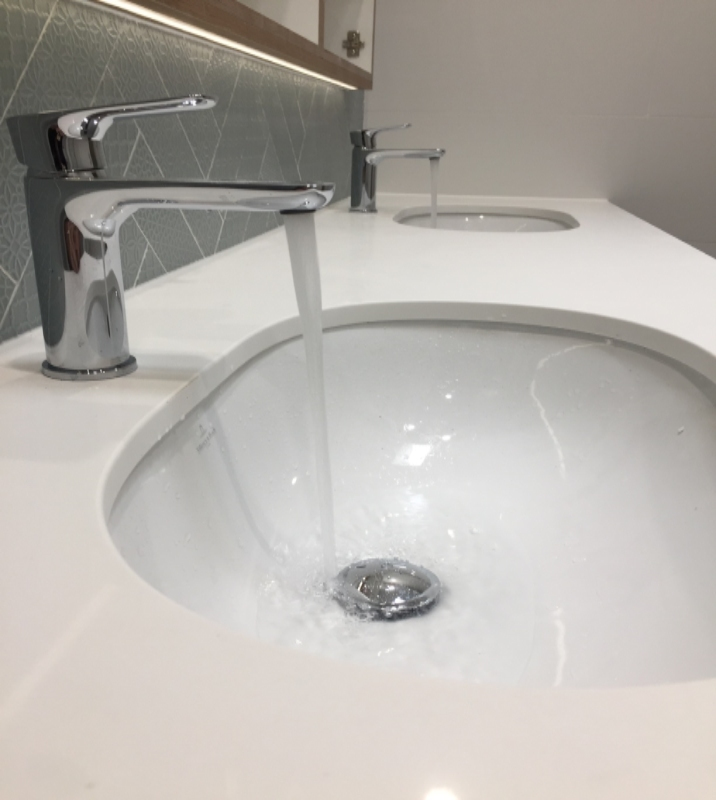 A white double sink basin with water pouring out of each tap.