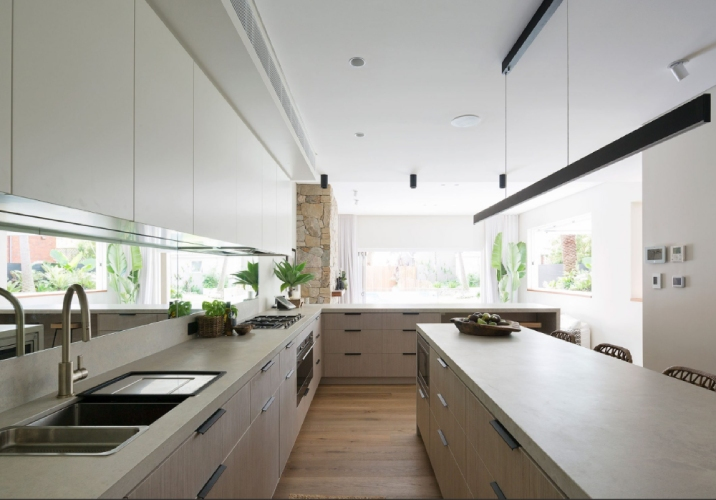 Large kitchen with island bench, mirrored splashback and timber cabinetry.