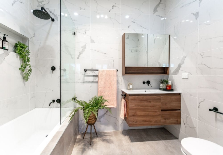 Modern bathroom with marble wall tiles, timber basin and shower/bath.