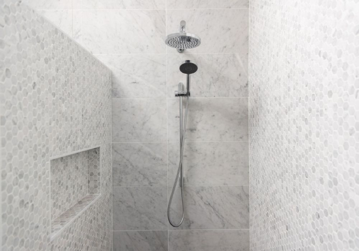 New honeycomb tiled shower with two shower heads.