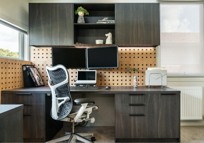 Home office with ergonomic chair, laptop, two monitors and desk.