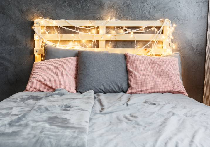 A bed with a pallet bedhead and lights