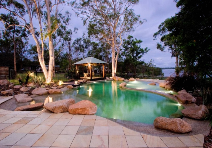 Large backyard with big pool surrounded by large gum trees and water views