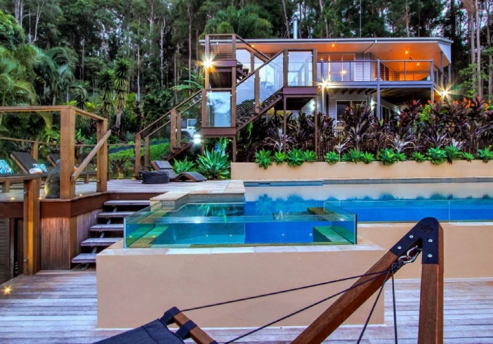 Large backyard of a two storey house containing an infinity pool and deck