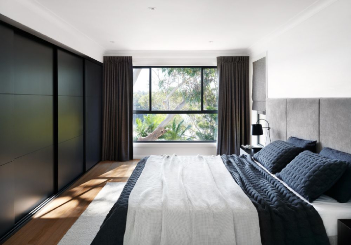 Bedroom with large bed, brown curtains and black cupboards
