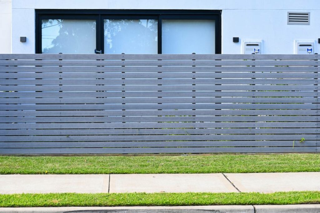A grey horizontal slat wooden fence simply elevates the property