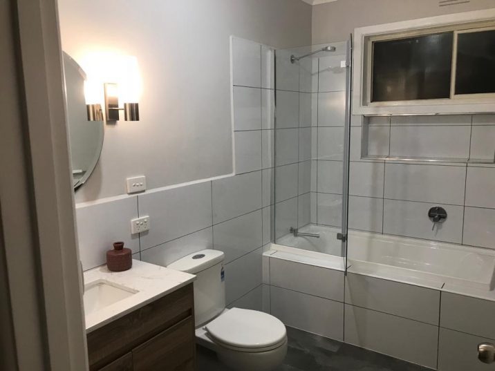 Renovated white bathroom with fresh and modern shower, toilet and basin.