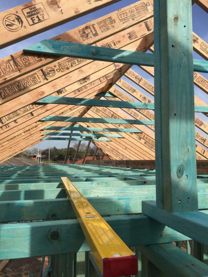 Timber structure of a roof truss with yellow level.