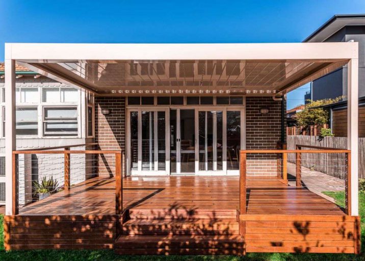 Backyard timber decking area with retractable steel pergola leaning from house