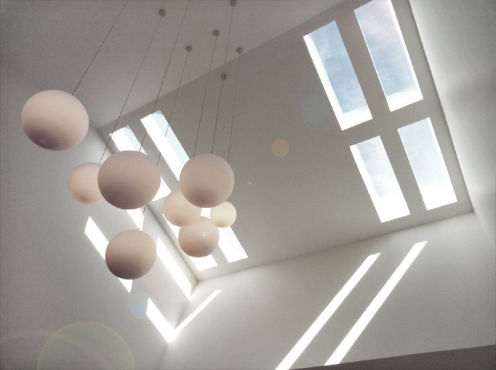 Ceiling of a house with two rectangular skylights with hanging lights.