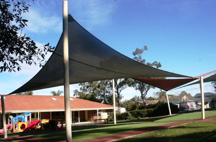 Large black outdoor shade sail in the backyard of a home.