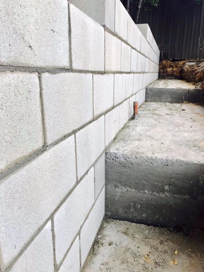 Close up image of a grey brick fence in the construction phase.