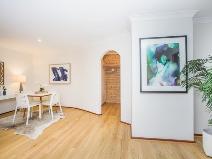 Timber floored room with white walls, dining table, chairs and paintings on the walls.