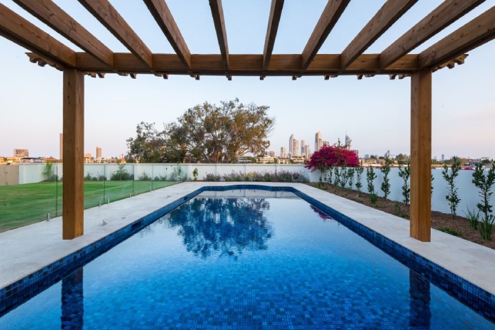 Large blue tiled inground pool with a view of a city landscape.