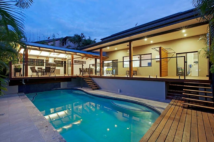 Modern backyard with with a pool surrounded by an L shaped decking area.