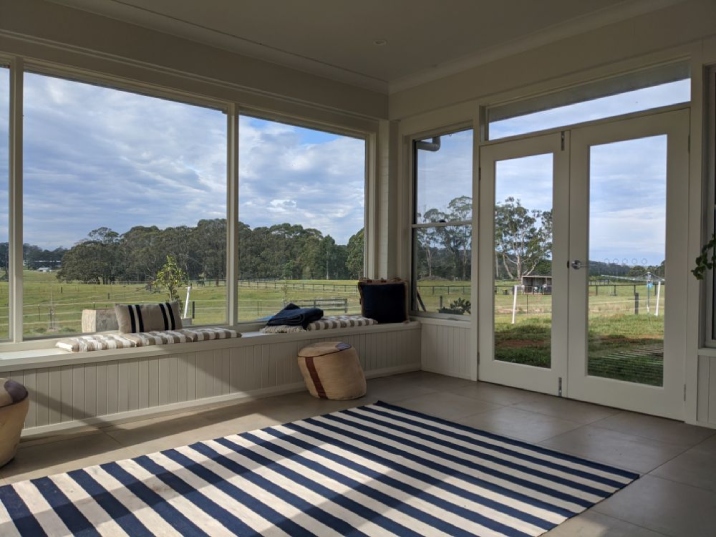 Bright room with large windows and doors overlooking a green paddock.