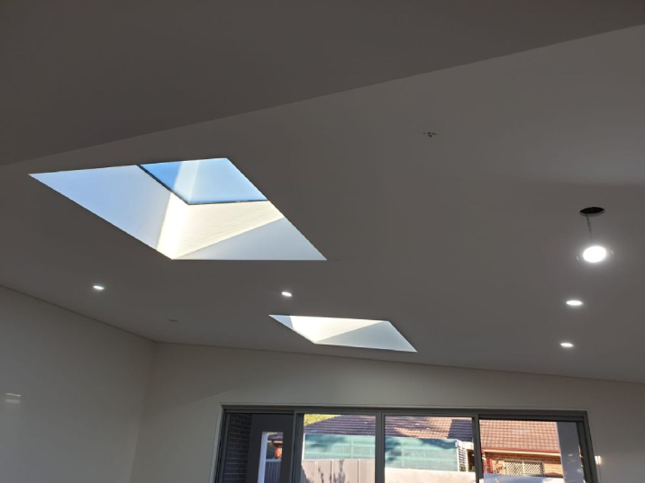 Two square skylights on a white ceiling in a dining room.