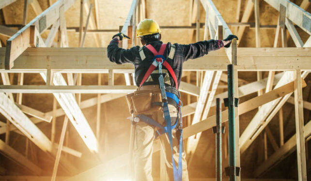 Australian framing standards - Carpenter securing wooden trusses inside a partially built structure.