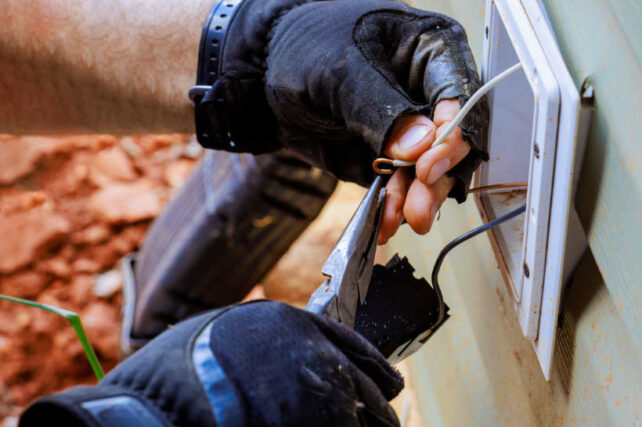 Phone socket wiring Australia - Technician wiring an external telephone socket with pliers