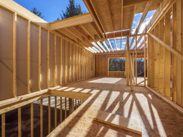 Australian framing standards - Sunlit interior of a partially built wooden house with exposed framing.