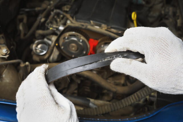 an auto mechanic showing a damaged timing belt